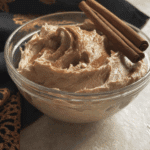Glass bowl filled with creamy Brown Sugar Cinnamon Butter, topped with cinnamon sticks.
