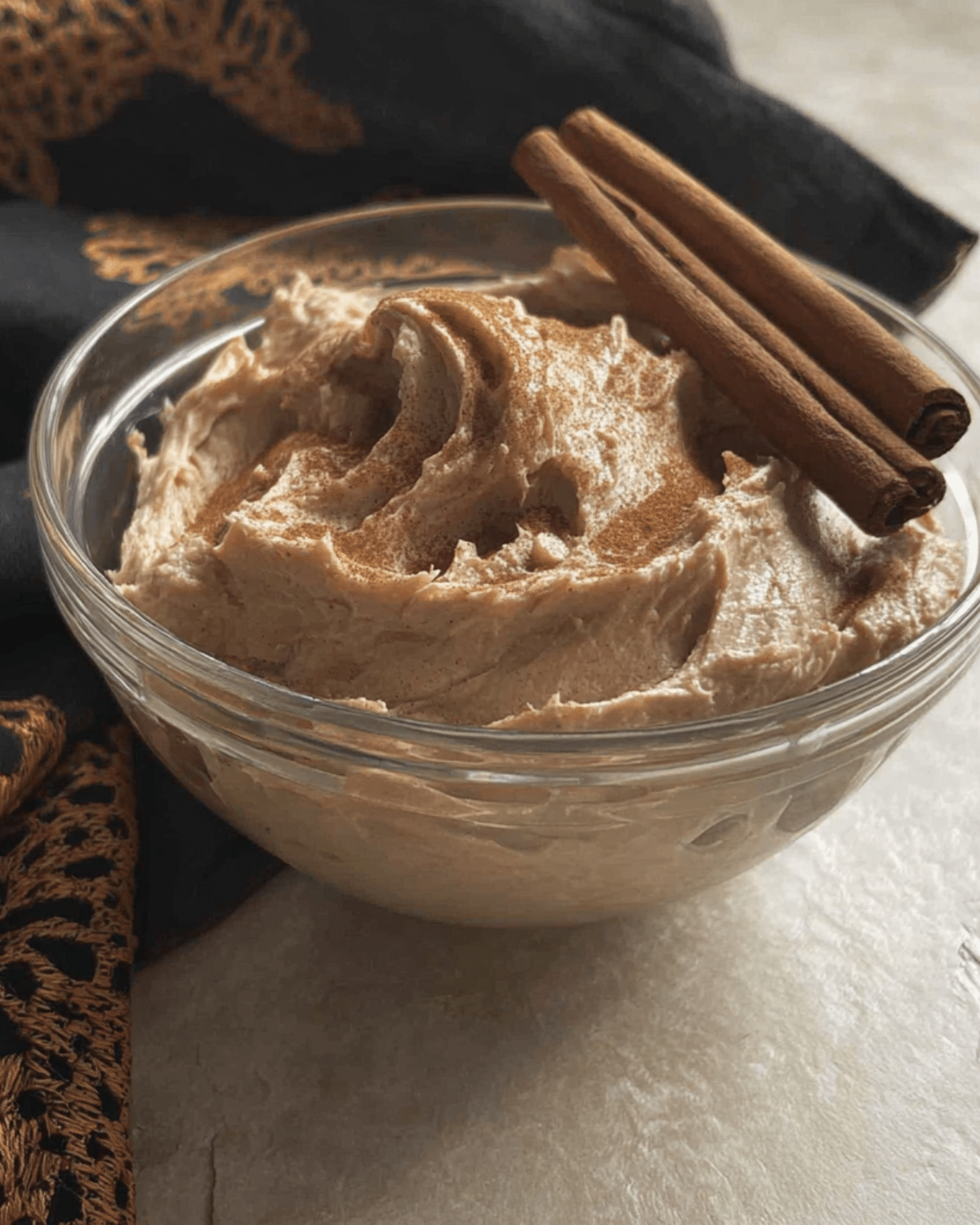 Glass bowl filled with creamy Brown Sugar Cinnamon Butter, topped with cinnamon sticks.