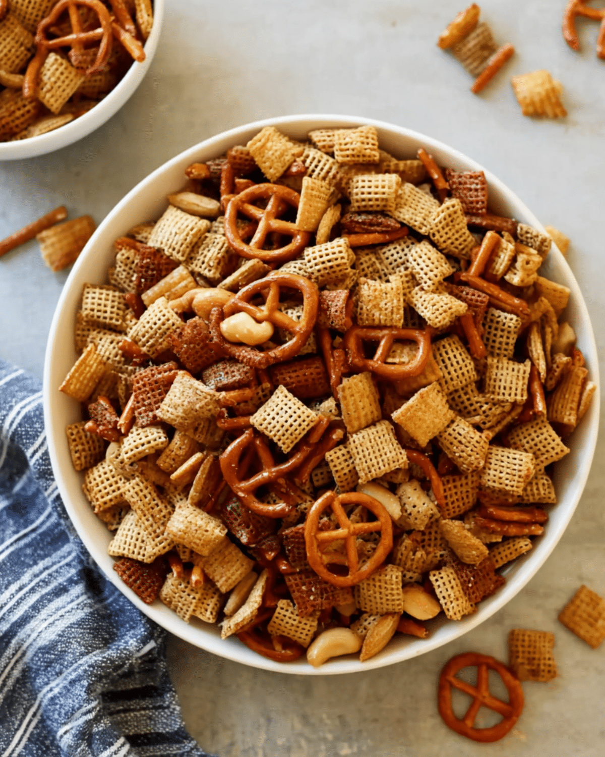 A bowl filled with Chex party mix, including pretzels, mixed Chex cereals, nuts, and seasoning.