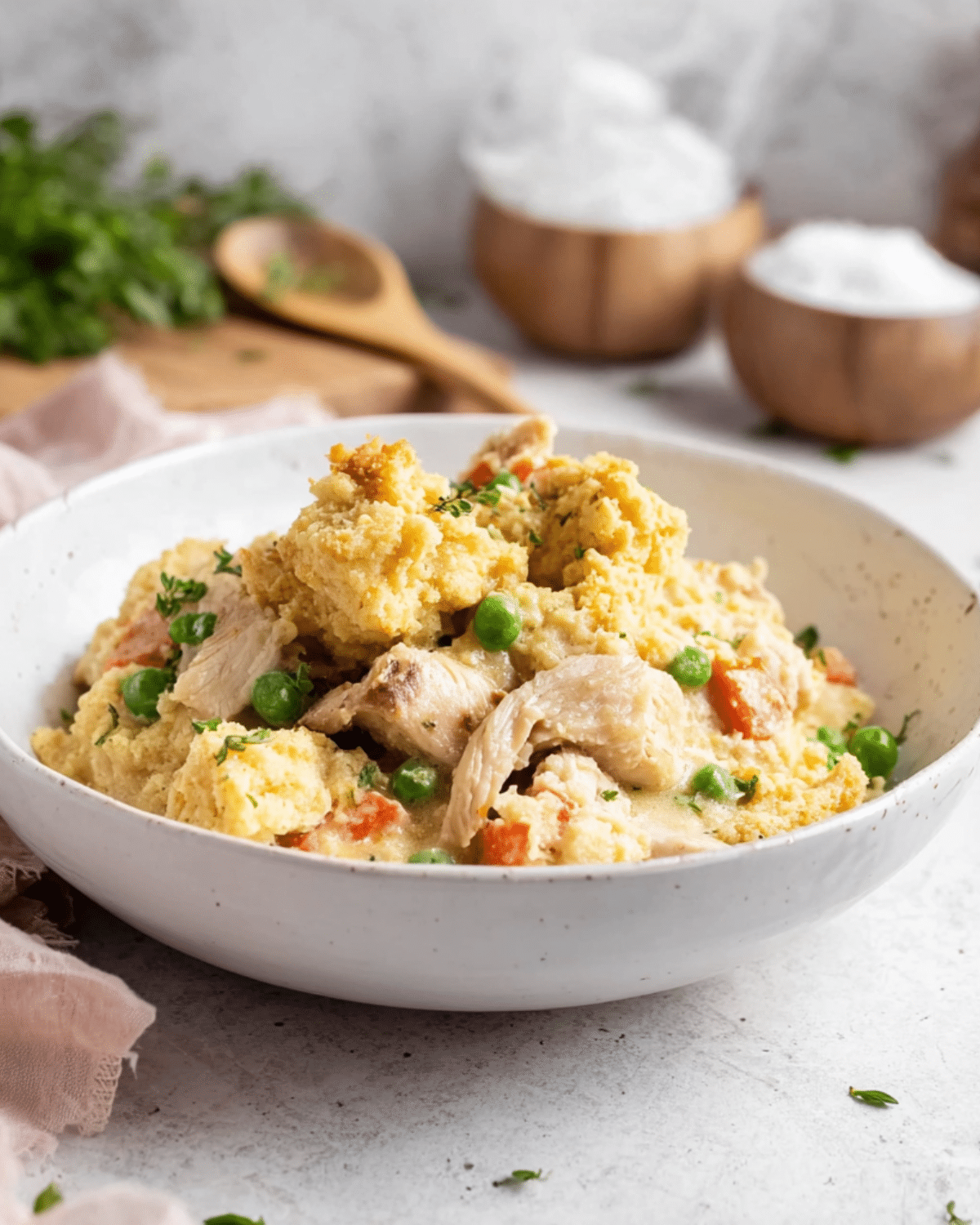 Creamy Chicken Cobbler served in a white bowl, featuring shredded chicken, peas, carrots, and golden biscuit topping.