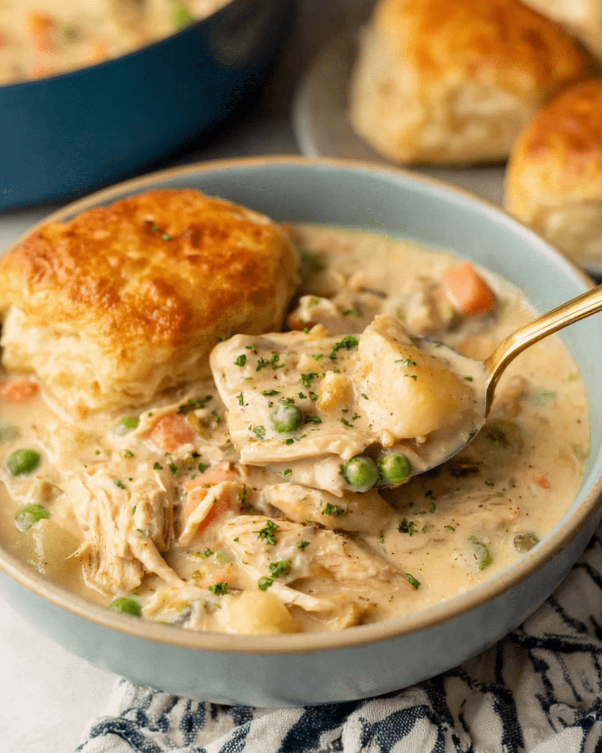 Bowl of creamy chicken pot pie soup with vegetables and a golden biscuit on top