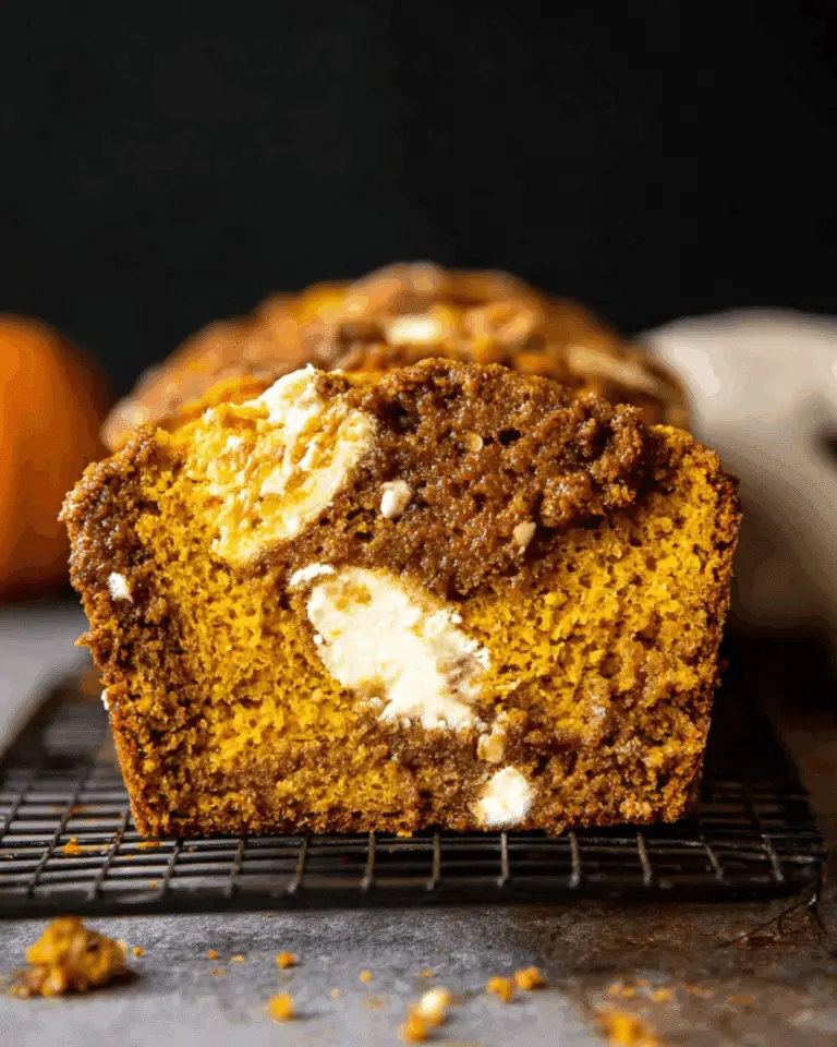 Close-up of a slice of cream cheese swirled pumpkin butter bread on a cooling rack.