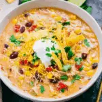 Bowl of Crockpot Chicken Tortilla Soup topped with shredded cheese, sour cream, tortilla strips, and fresh cilantro.
