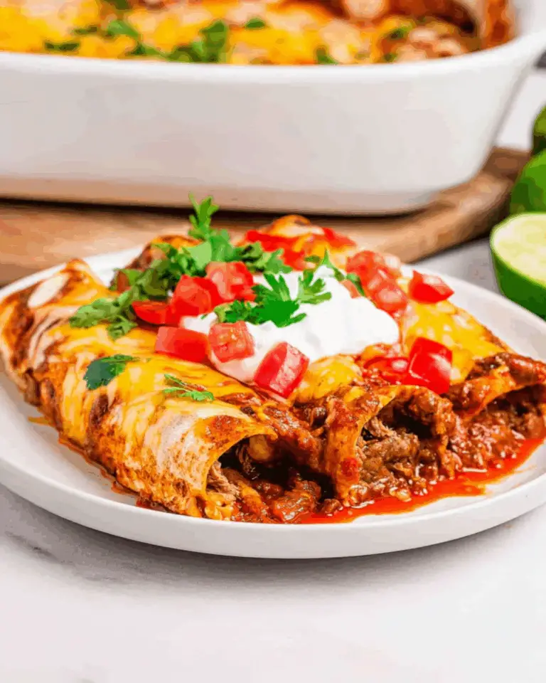 Plate of lazy enchiladas filled with seasoned meat, topped with melted cheese, sour cream, chopped tomatoes, and cilantro.