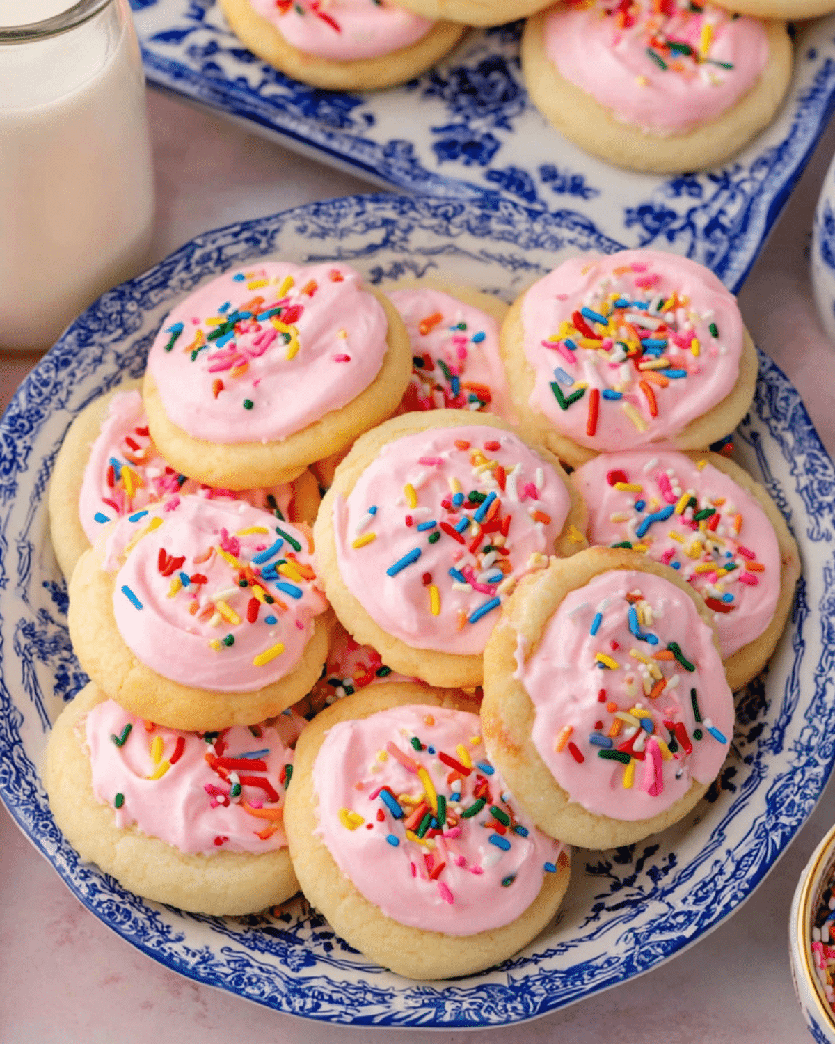 Plate of Lofthouse Cookies topped with pink frosting and rainbow sprinkles.