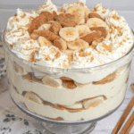 Glass trifle bowl filled with layers of Magnolia Bakery banana pudding, sliced bananas, vanilla wafers, and whipped cream.