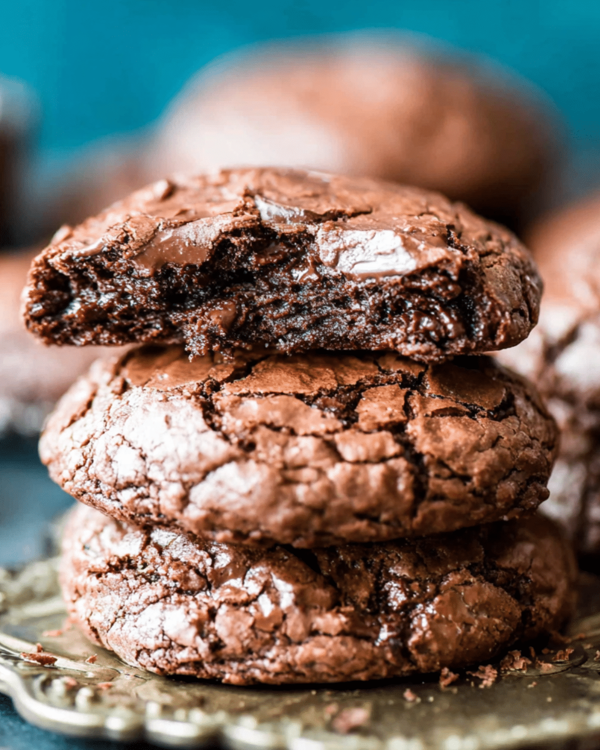 Stack of gooey Magic Brownie Cookies with a fudgy center and crackly tops, one with a bite taken out.