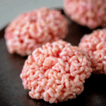 Close-up of Marshmallow Rice Krispies Halloween Brains shaped like pink brains on a dark surface.