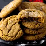Close-up of soft Molasses Cookies coated with sugar, stacked on a dark plate.