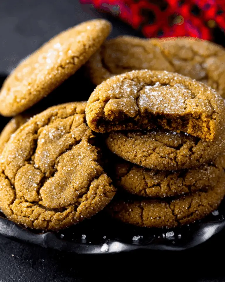 Close-up of soft Molasses Cookies coated with sugar, stacked on a dark plate.