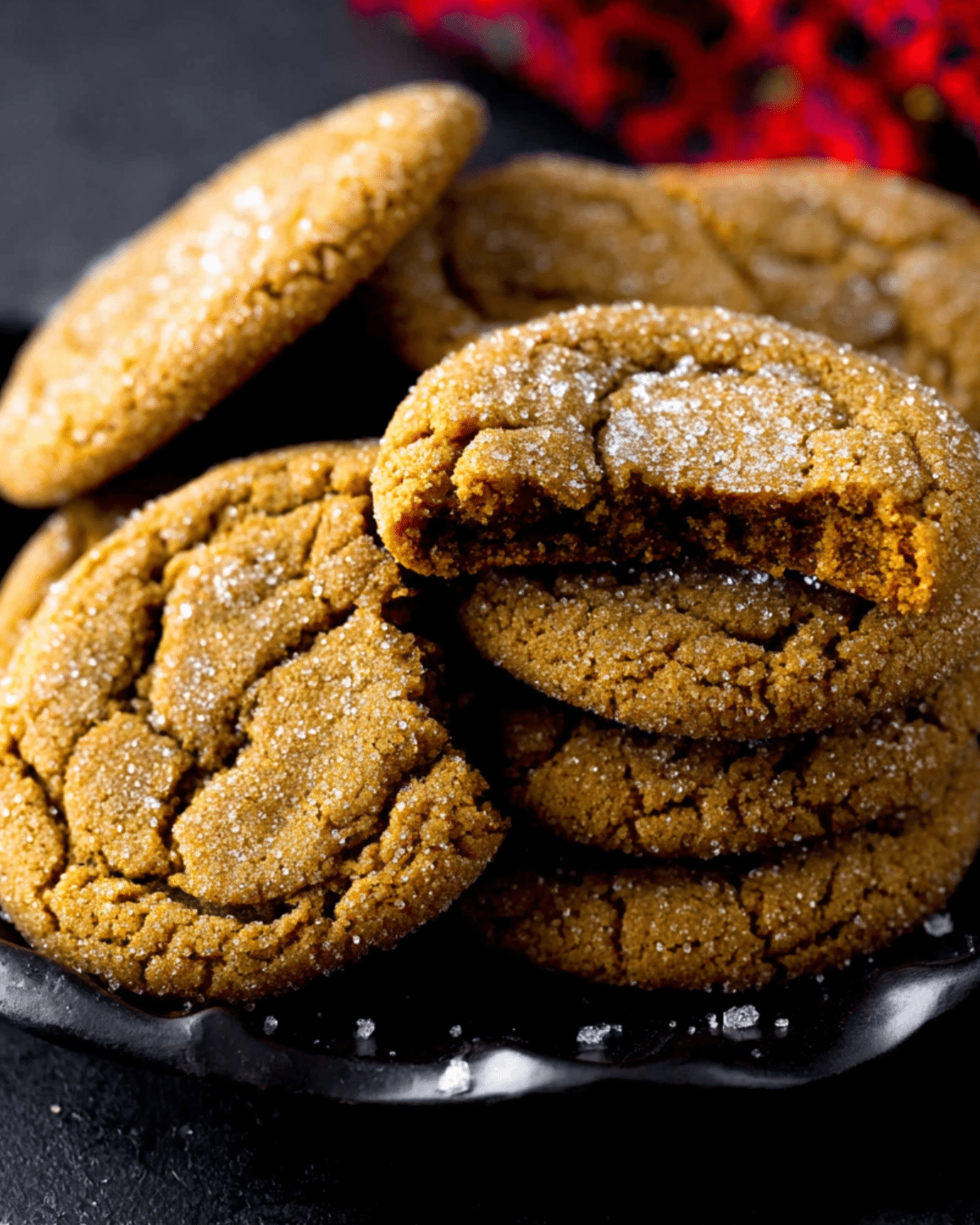 Close-up of soft Molasses Cookies coated with sugar, stacked on a dark plate.