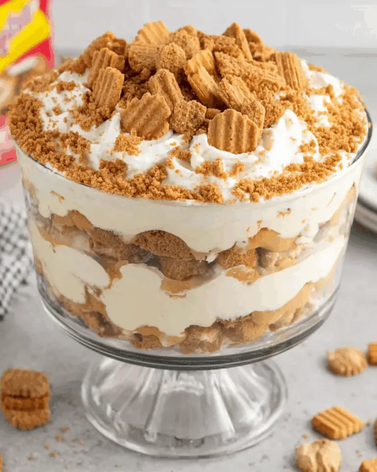 Glass trifle dish filled with layers of Nutter Butter trifle, including crushed cookies, creamy pudding, and whipped topping.
