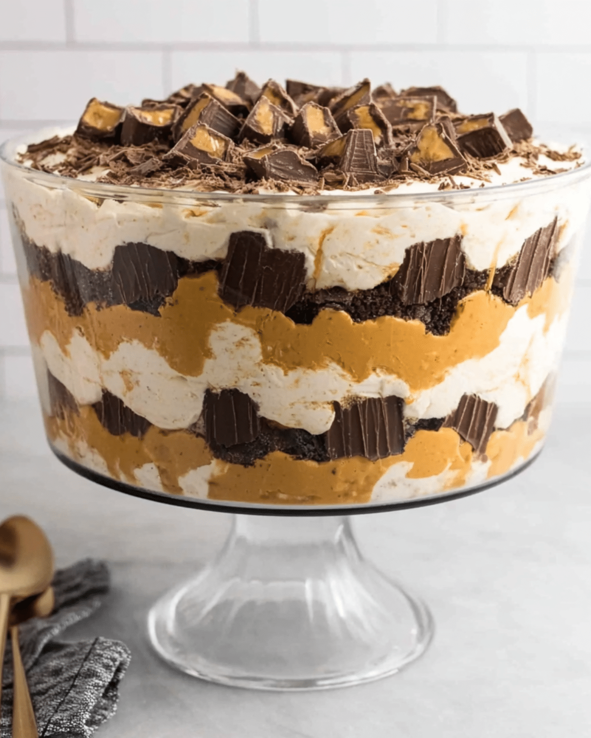 Layered Reese's Peanut Butter Trifle with whipped cream, chocolate cake, peanut butter filling, and chopped Reese's cups.