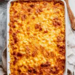 A golden, cheesy dish of Southern baked macaroni and cheese in a white casserole dish with crispy, browned edges.