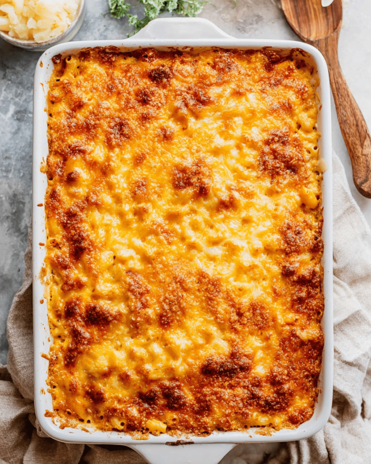 A golden, cheesy dish of Southern baked macaroni and cheese in a white casserole dish with crispy, browned edges.