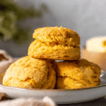 Fluffy sweet potato biscuits stacked on a white plate, with a soft golden-brown crust.