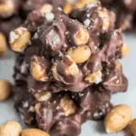 Close-up of toffee peanut clusters made with roasted peanuts coated in rich chocolate and sprinkled with sea salt.