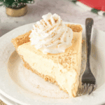 Slice of creamy eggnog pie with whipped cream and a sprinkle of nutmeg on a white plate.
