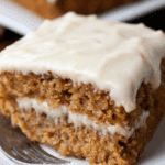 Slice of moist Applesauce Cake with creamy frosting between layers and on top.