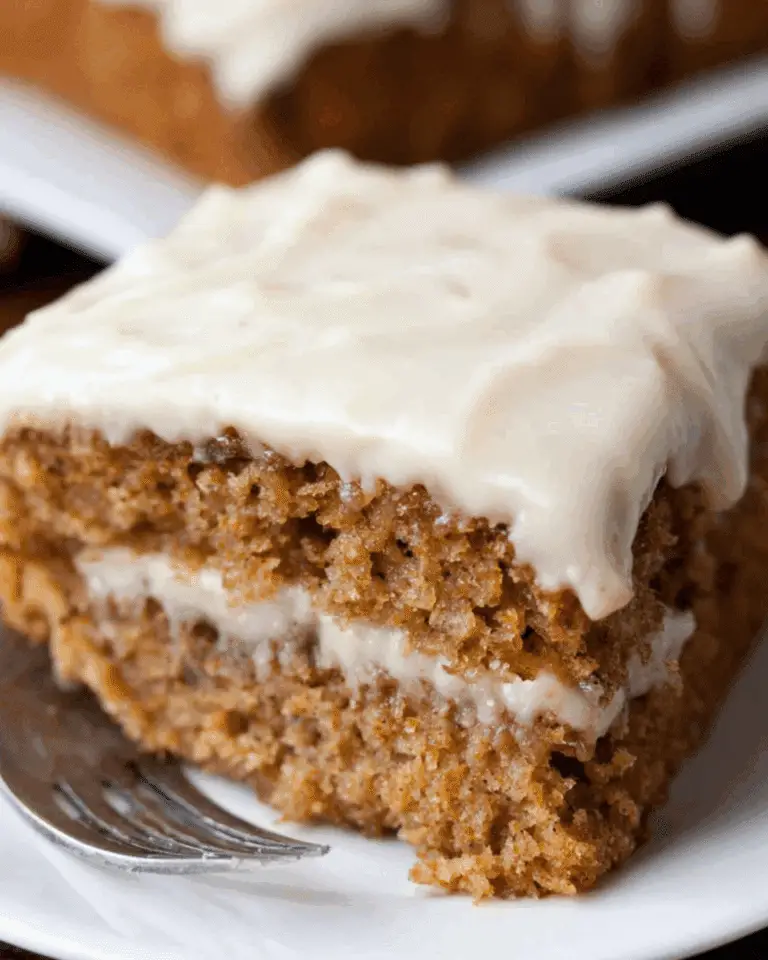 Slice of moist Applesauce Cake with creamy frosting between layers and on top.