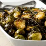 Roasted Balsamic Glazed Brussels Sprouts served in a white dish with fresh herbs.