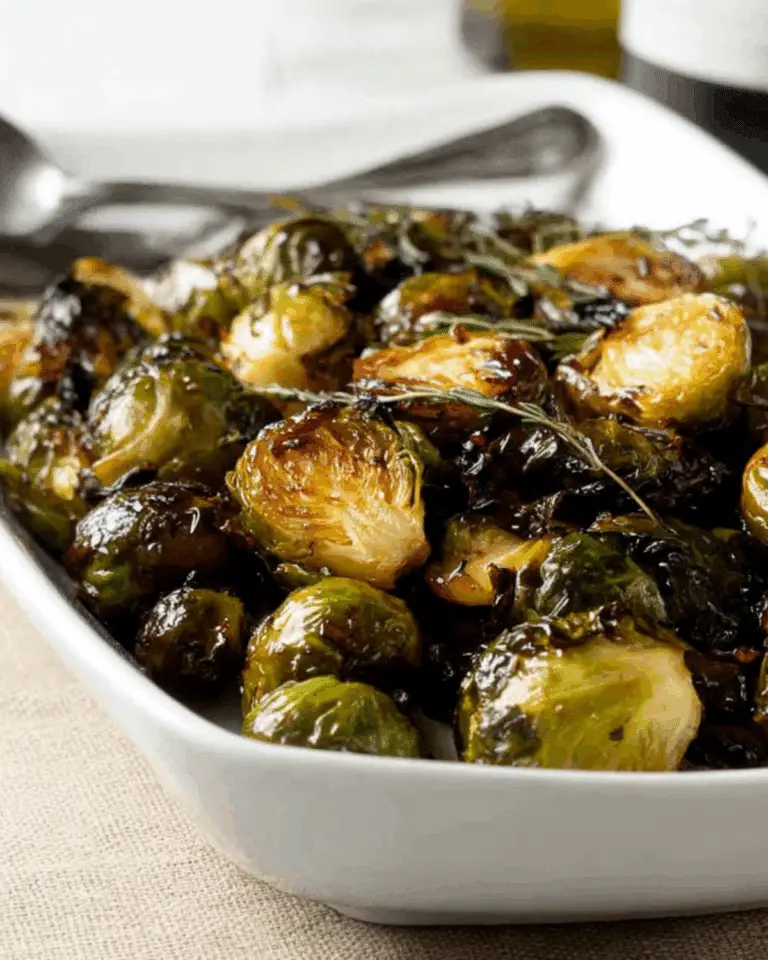 Roasted Balsamic Glazed Brussels Sprouts served in a white dish with fresh herbs.