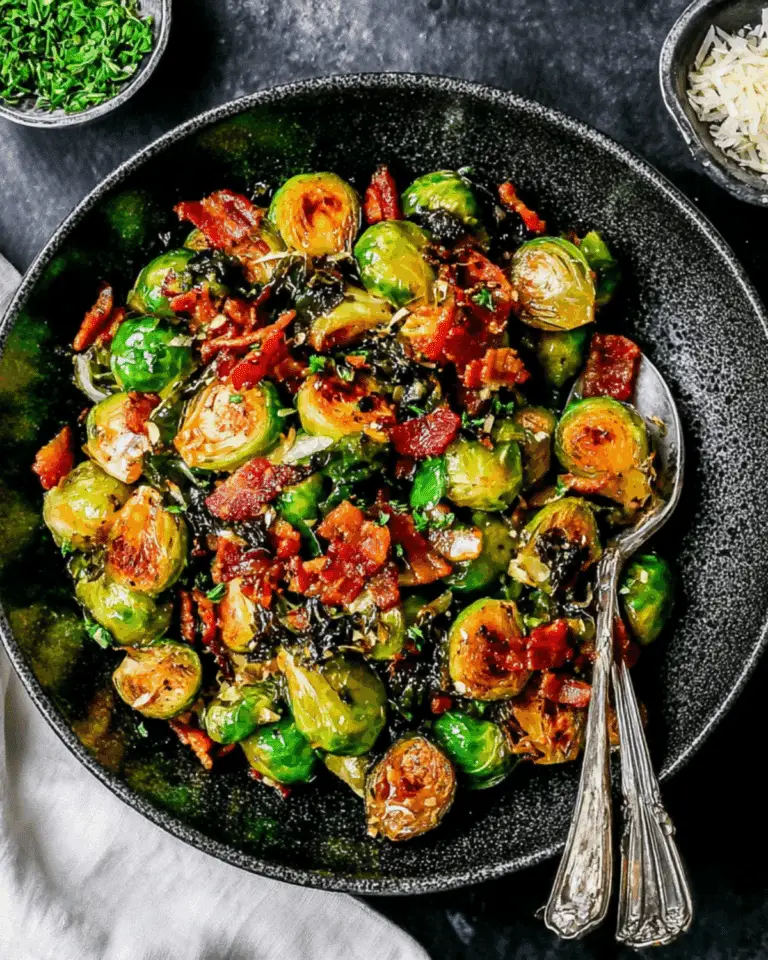 A bowl of roasted Brussels sprouts with crispy bacon pieces, garnished with herbs and served with a spoon.