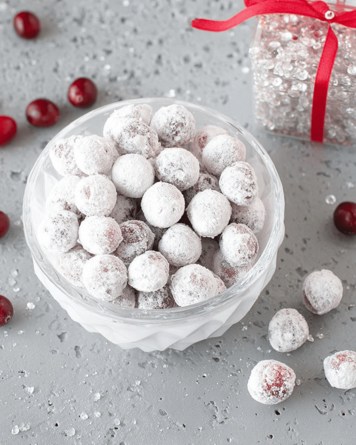 Bowl of candied cranberries coated in sugar on a festive grey background