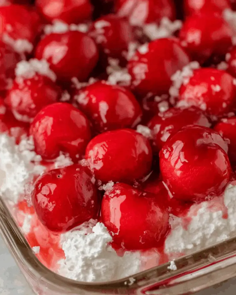 Close-up of Cherries in the Snow dessert with bright red cherries and fluffy whipped cream topping.