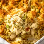Spoonful of chicken and stuffing casserole lifted from a golden-baked dish.