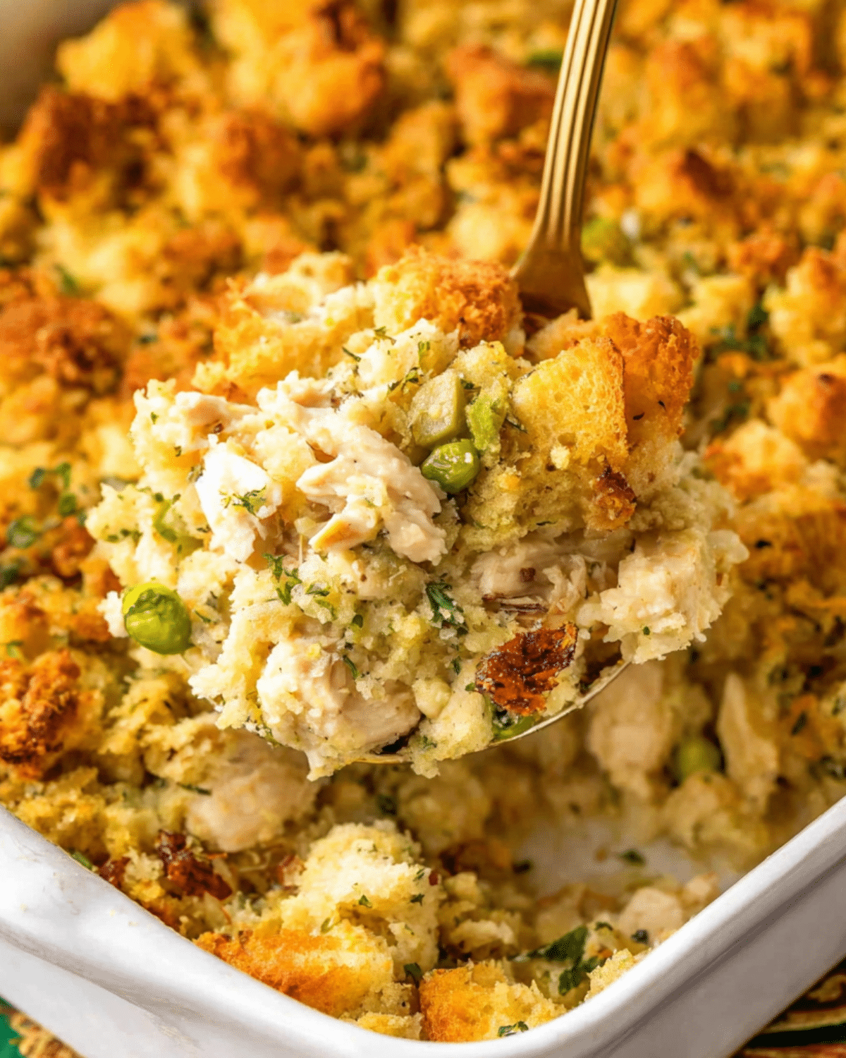 Spoonful of chicken and stuffing casserole lifted from a golden-baked dish.