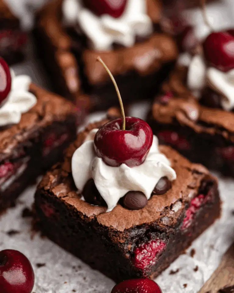 Rich chocolate cherry brownies topped with whipped cream, chocolate chips, and fresh cherries.