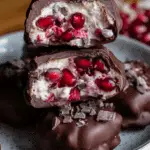 Chocolate Covered Pomegranate Yogurt Clusters stacked on a plate with visible pomegranate seeds and yogurt filling.