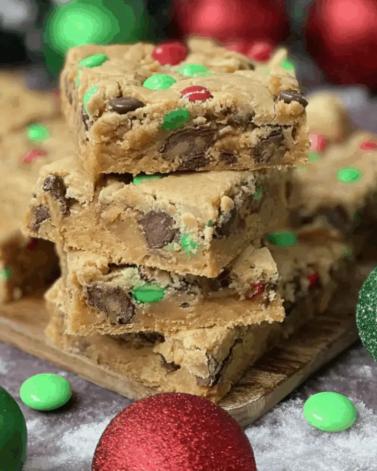 Stacked Christmas cookie bars filled with chocolate chips and red and green M&M candies, surrounded by festive holiday ornaments.