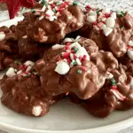 A plate of Christmas Crock Pot Candy topped with festive red, green, and white sprinkles and mini marshmallows.