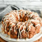 Cinnamon Roll Monkey Bread drizzled with icing and served on a white plate.