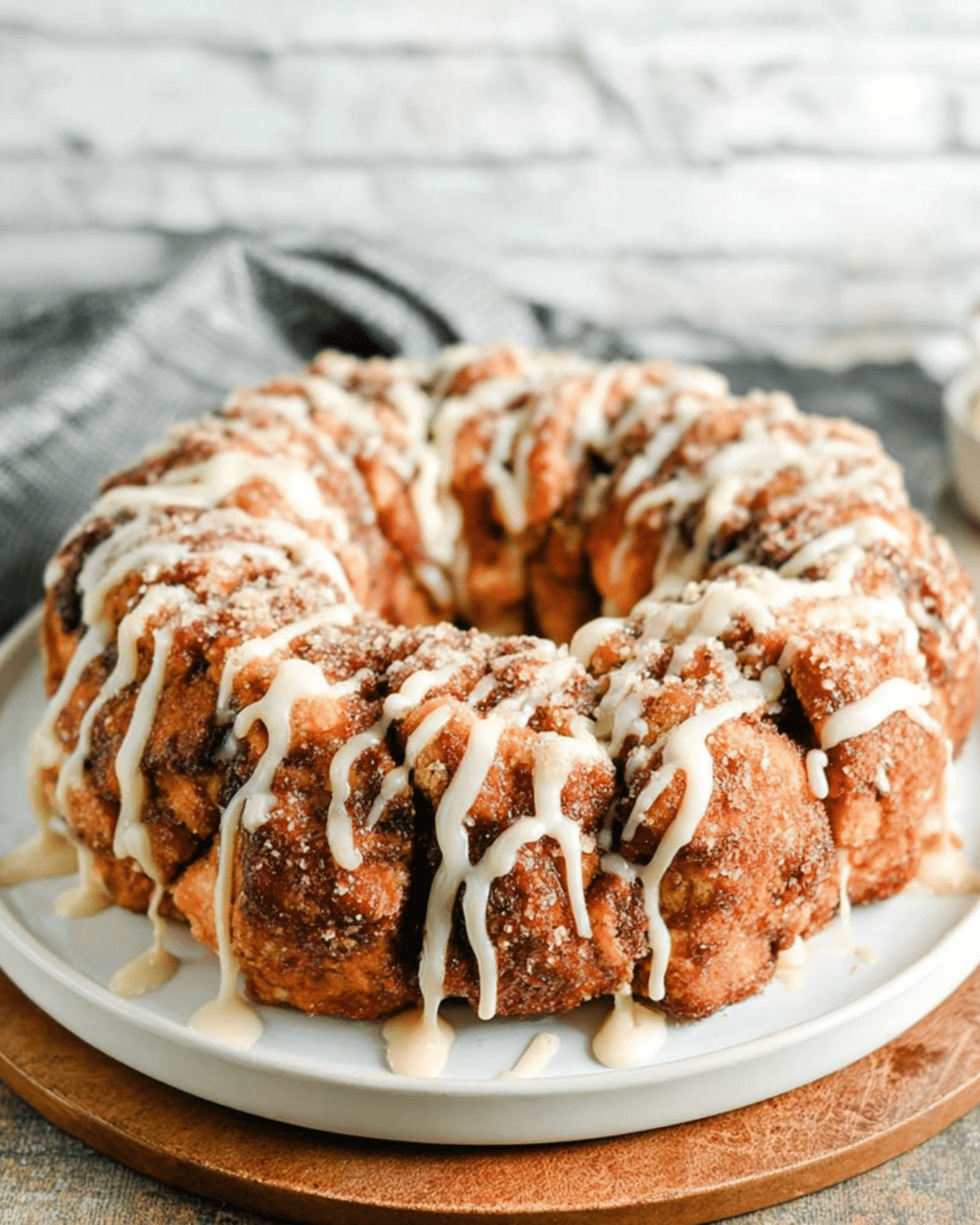 Cinnamon Roll Monkey Bread drizzled with icing and served on a white plate.