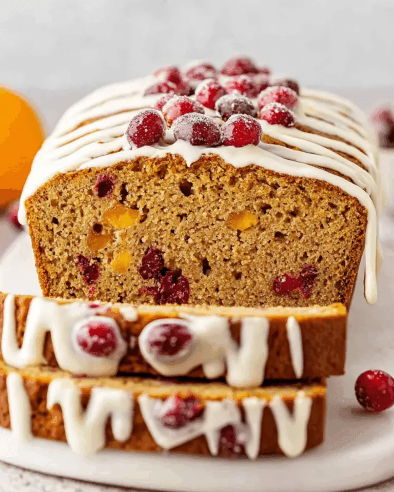 Sliced Cranberry Eggnog Bread topped with a white glaze and sugared cranberries.