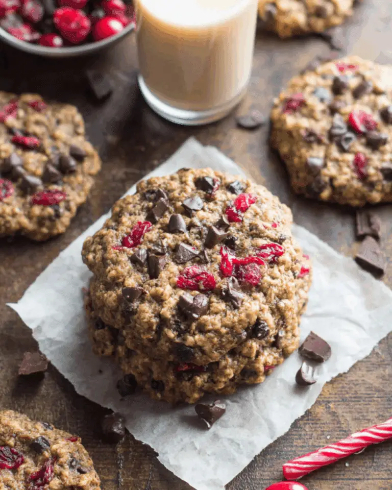 Dark Chocolate Cranberry Oatmeal Cookies stacked on parchment paper with scattered chocolate chunks