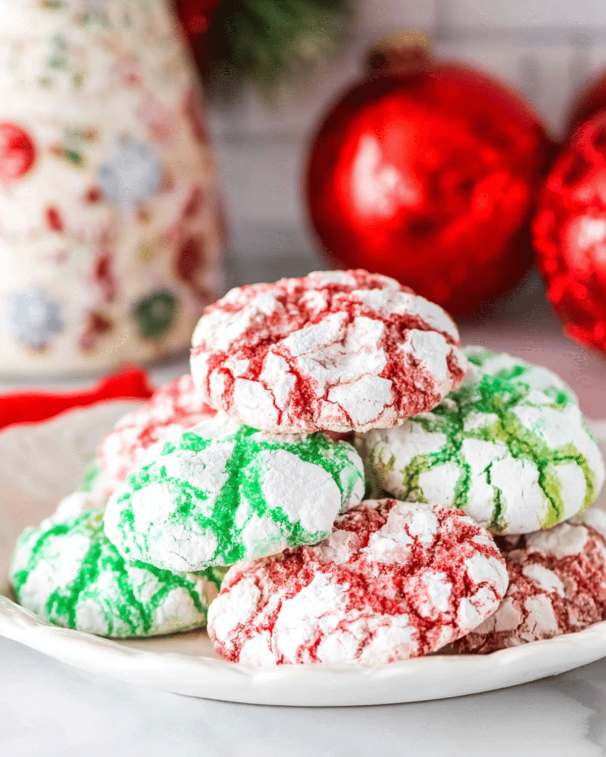 Plate of festive crinkle cookies in red and green colors, dusted with powdered sugar.