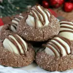 Plate of Gingerbread Kiss Cookies topped with white chocolate kisses and drizzled with milk chocolate.