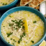 Bowl of Greek Lemon Chicken Soup garnished with fresh parsley and a lemon wedge.