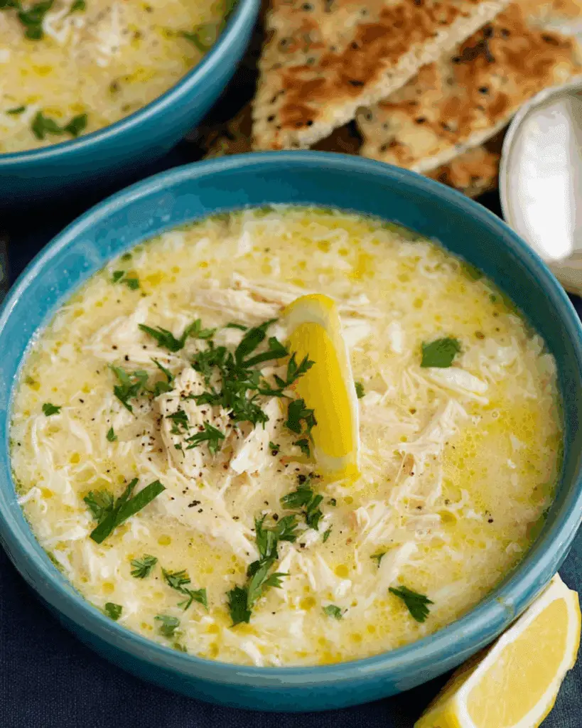 Bowl of Greek Lemon Chicken Soup garnished with fresh parsley and a lemon wedge.