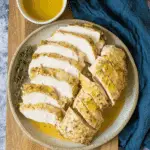 Sliced juicy slow cooker turkey breast served with herb gravy on a ceramic plate with a side of fresh thyme.