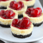 Mini cherry cheesecakes with Oreo crust, topped with glossy cherry pie filling on a white plate.