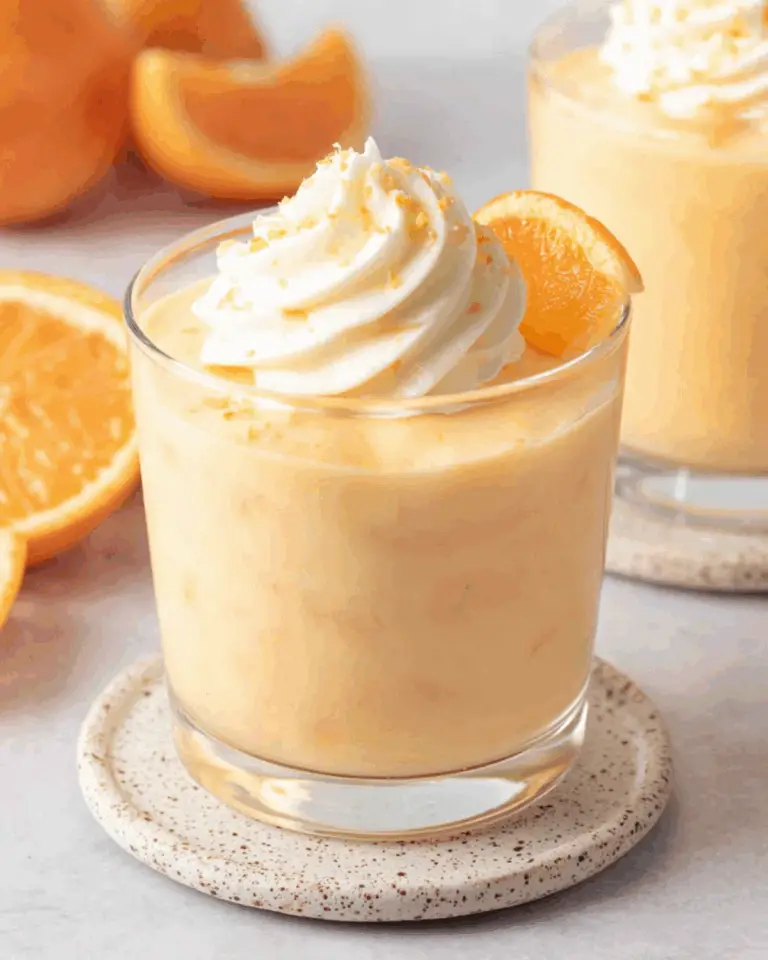 Creamy Orange Mousse Cups topped with whipped cream and an orange slice.
