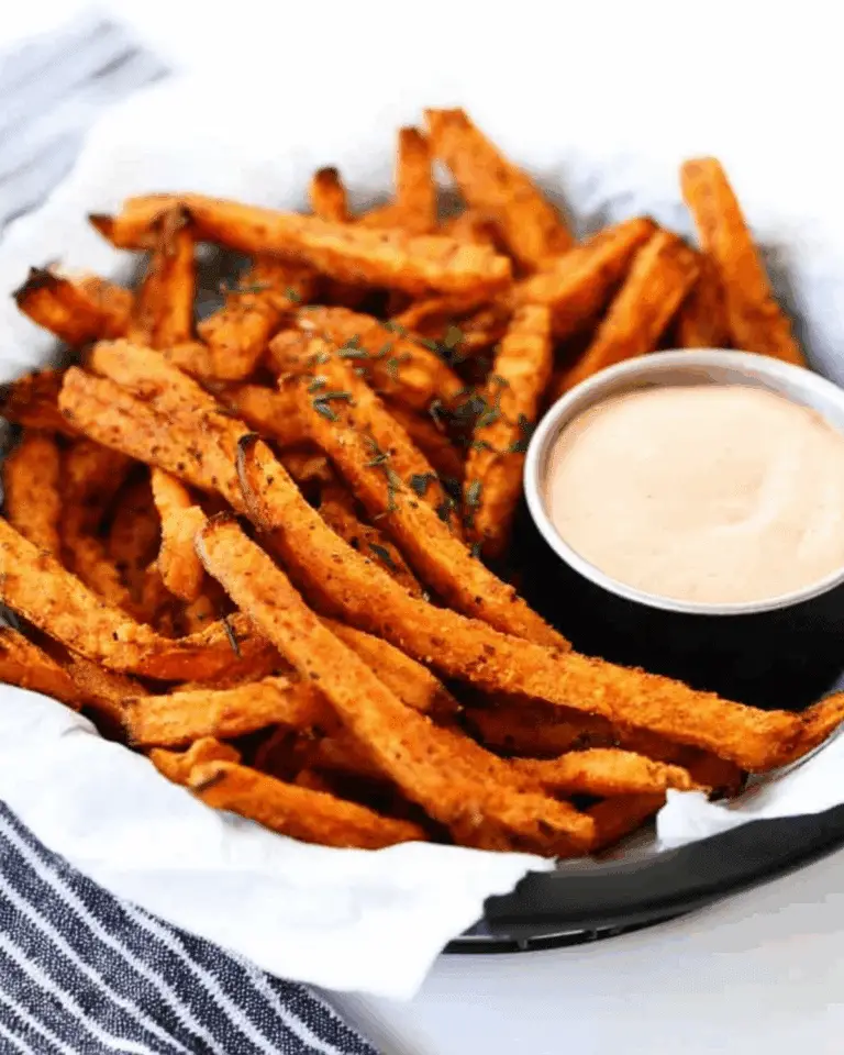 Crispy oven baked sweet potato fries served in a basket with a side of creamy dipping sauce.
