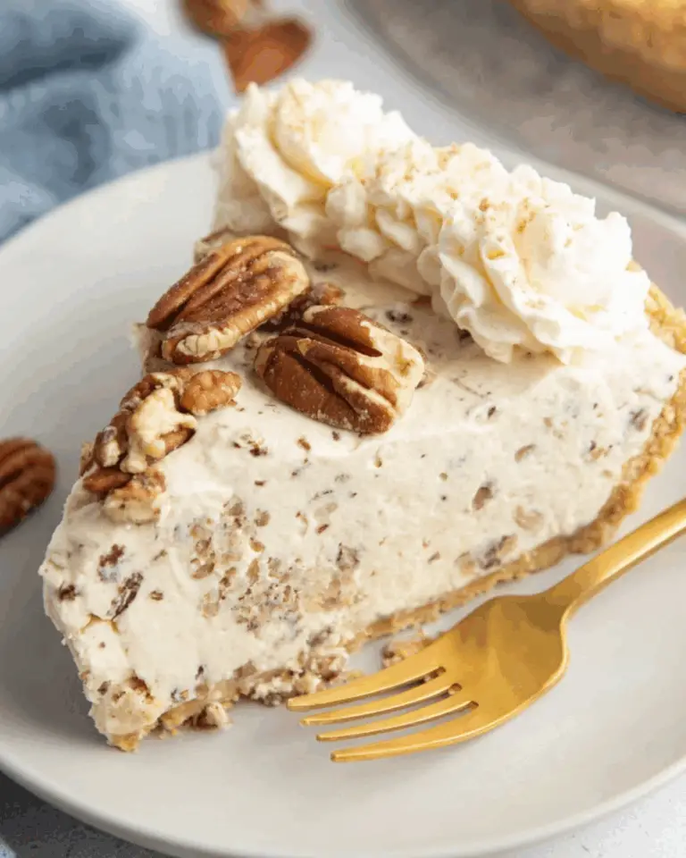 Slice of pecan cream pie topped with whipped cream and pecans on a white plate with a gold fork.