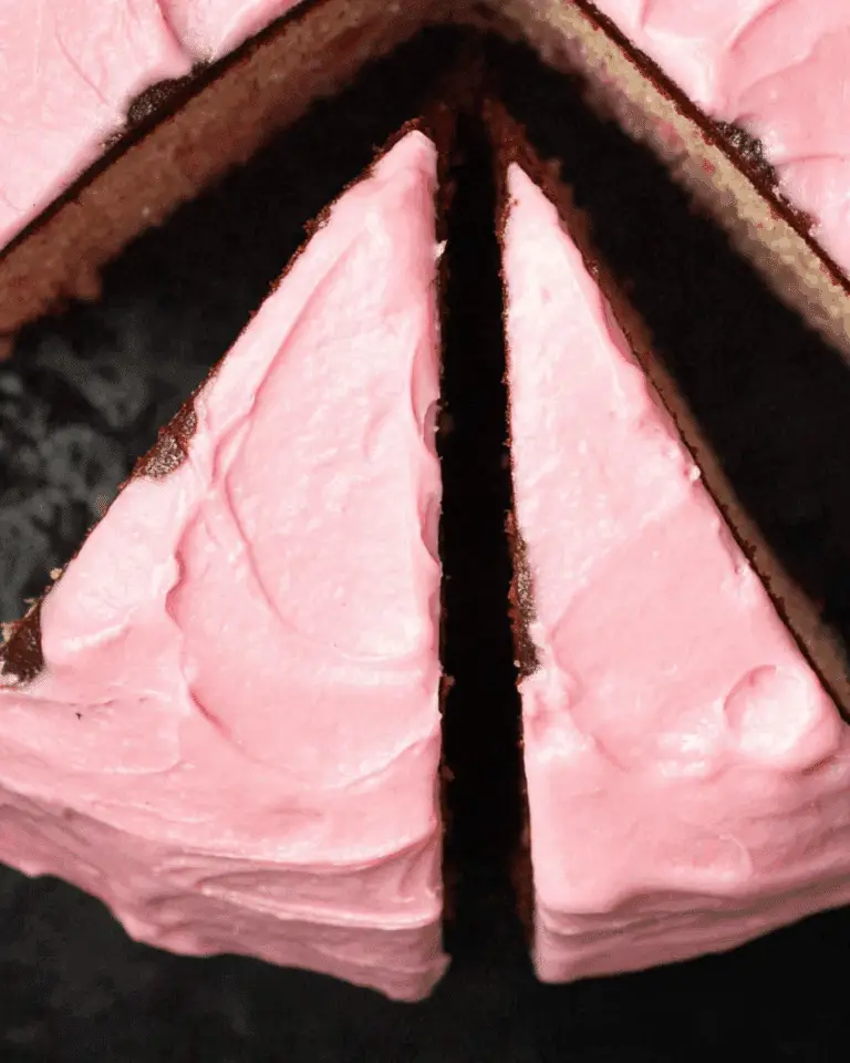 Close-up top view of a pink marble cake with chocolate layers and pink frosting, with two slices cut.