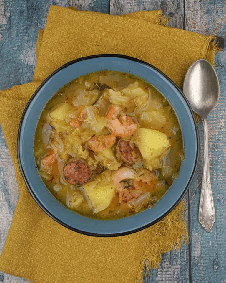 A bowl of Potato, Leek & Chorizo Soup with chunks of potatoes, sliced chorizo, shrimp, and leeks in a flavorful broth.